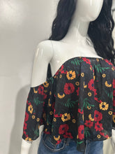 Load image into Gallery viewer, Blusa floral negra con estampado rojo y amarillo, corte off-shoulder, combinada con mahones cortos


